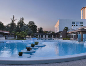 foto di una piscina presente nel Continental Terme Hotel, con sfondo hotel e palazzi.